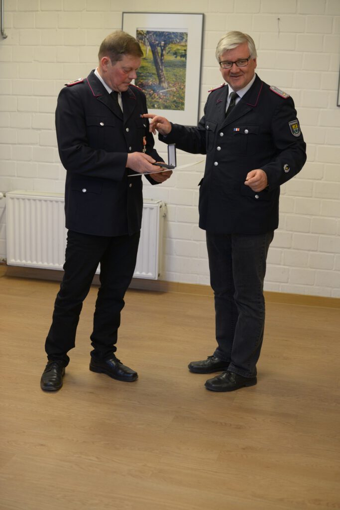 Wehrführer Attila Kuczmann überreicht das Brandschutzehrenzeichen am Bande für 40-Jahre Feuerwehrdienst an Jens Reese